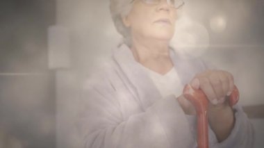 Yürüme çubuğuna yaslanmış dalgın yaşlı bir kadının üzerinde parlayan ışığın animasyonu. emeklilik ve yaşlı yaşam konsepti dijital olarak oluşturulmuş video.