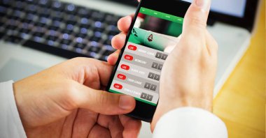 Ahşap masadaki dizüstü bilgisayara karşı akıllı telefonu kullanarak elinizi kapatın. dijital arayüz ve modern teknoloji kavramı