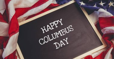 Arka planda Amerikan bayrağına karşı tahta tahtayla ilgili Columbus Günü metnin kutlu olsun. Columbus Günü şablon arkaplan tasarımı kavramı