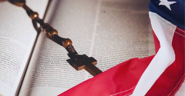 Amerikan bayrağını İncil 'in üzerinde çapraz tespihle sallıyor. Amerikan vatanseverliği ve din arka plan tasarımı kavramı