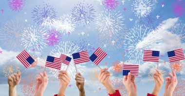 Amerikan bayraklarını havai fişeklerin üstünde tutan el kompozisyonu. Amerikan vatanseverliği, bağımsızlık ve dijital olarak üretilen görüntü konsepti.