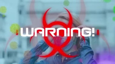 Biyolojik tehlike sembolü ve yüz maskesi takmış kadın üzerindeki Coperid 19 veri işleme ve hücrelerinin animasyonu. küresel covid 19 salgın konsepti dijital olarak oluşturulmuş video.