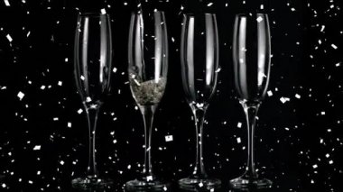 Şampanya bardaklarının ve konfetilerin siyah arka plana düşüşünün animasyonu. kutlama ve parti konsepti dijital olarak oluşturulmuş video.