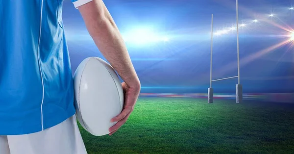 Composition of male rugby player holding ball at stadium. sport and competition concept digitally generated image.