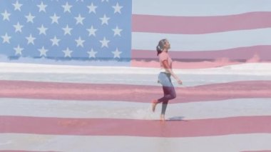 Amerikan bayrağının animasyonu sahilde dans eden kadının üzerinde hareket ediyor. Vatanseverlik ve kutlama konsepti dijital olarak oluşturulmuş video.