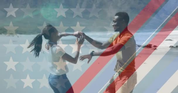アフリカ系アメリカ人のカップルがビーチで踊るアメリカ国旗のアニメーション 愛国心とお祝いのコンセプトをデジタルで — ストック動画