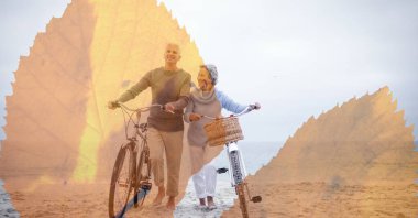 Sahilde bisikletle yürüyen yaşlı çifte karşı yaprakların dijital kompozit görüntüsü. emekli çift yaşam tarzı konsepti