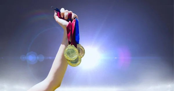 灰色の背景に光のスポットに対して複数のメダルを保持する手を閉じる スポーツ大会や競技会のコンセプト — ストック写真