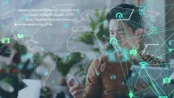 世界地図上のデジタルアイコンやデータ処理の世界は 自宅でスマートフォンを使用してアジアの男に対して 世界的なネットワーキングとテクノロジーの概念 — ストック動画