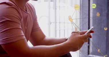 Evinde akıllı telefon kullanarak beyaz adama karşı dönen dijital simgeler küresi. küresel ağ ve teknoloji kavramı