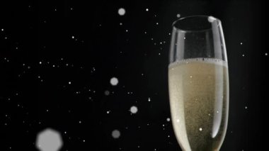 Siyah arka planda şampanya kadehinin üzerinde beyaz beneklerin yüzüşü. kutlama ve yeni yıl partisi konsepti dijital olarak oluşturulmuş video.