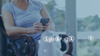 Evde akıllı telefon kullanan Kafkasyalı yaşlı kadınlara karşı birden fazla profil ve dijital simgeler. küresel ağ ve teknoloji kavramı