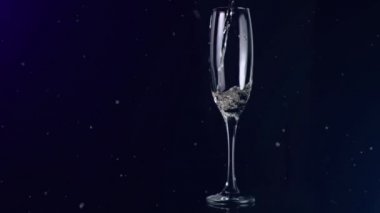 Siyah arka planda şampanya kadehinin üzerinde beyaz beneklerin yüzüşü. kutlama ve yeni yıl partisi konsepti dijital olarak oluşturulmuş video.