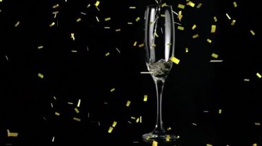 Siyah arka planda bir bardak şampanyanın üzerine düşen altın konfetilerinin animasyonu. kutlama ve yeni yıl partisi konsepti dijital olarak oluşturulmuş video.
