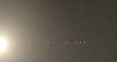 Gece gökyüzündeki yıldızların üzerinde hipnotize edici bir hareketle hareket eden parlayan sarı yıldız ışığı görüntüsü. Işık rengi ve hareket kavramı dijital olarak oluşturuldu.