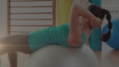 İsviçre topunda egzersiz yapan bir kadının üzerinde parlayan ışığın canlandırması. fitness ve sağlıklı yaşam tarzı konsepti dijital olarak oluşturulmuş video.