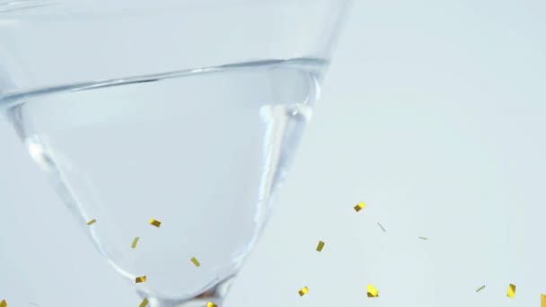 Animatie Van Goud Confetti Vallen Heldere Drank Glas Witte Achtergrond — Stockvideo