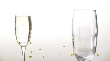 Beyaz arka planda şampanya bardaklarının üzerine düşen konfeti animasyonu. parti ve kutlama konsepti dijital olarak oluşturulmuş video.