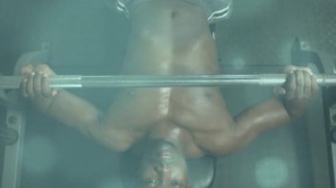 Spor salonunda egzersiz yapan zinde bir adamın üzerinde parlayan ışığın animasyonu. global spor, fitness ve veri işleme konsepti dijital olarak oluşturulmuş video.