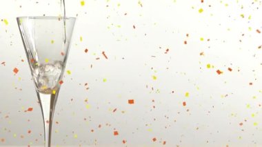 Beyaz arka planda şampanya bardağının üzerine düşen konfeti animasyonu. parti ve kutlama konsepti dijital olarak oluşturulmuş video.