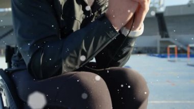 Tekerlekli sandalyede oturan adamın üzerine akıllı telefon kullanarak kar düşüşünün animasyonu. Spor ve yarışma konsepti dijital olarak oluşturulmuş video.