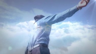 Doğada mavi gökyüzüne karşı dinlenen kollarını açmış bir adamın üzerinde parlayan ışığın animasyonu. Doğa, tatil ve yaz konsepti dijital olarak üretilen video.