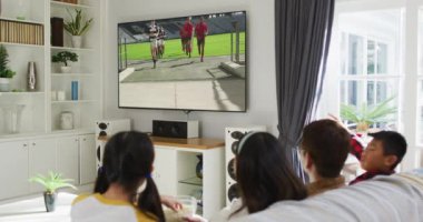 Mutlu bir ailenin evde oturup televizyonda rugby maçı izlemesinin birleşimi. spor, rekabet, eğlence ve teknoloji konsepti dijital olarak oluşturulmuş video.