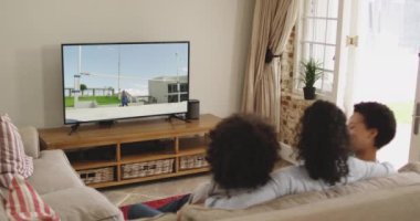Mutlu bir ailenin evde oturup TV 'de yüksek atlama atletizm izlemesinin birleşimi. spor, rekabet, eğlence ve teknoloji konsepti dijital olarak oluşturulmuş video.