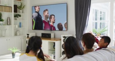 Mutlu bir ailenin evde oturup TV 'de spor müsabakalarını izlemesinin birleşimi. spor, rekabet, eğlence ve teknoloji konsepti dijital olarak oluşturulmuş video.