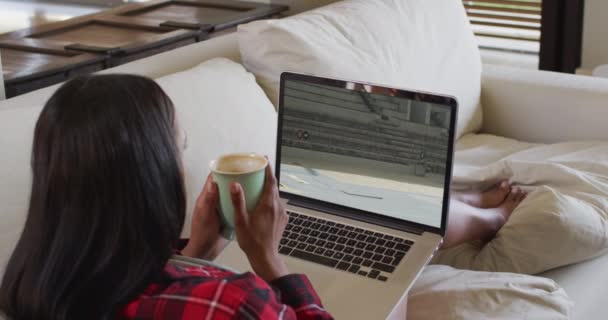 Compuesto Mujer Sentada Casa Sosteniendo Café Viendo Atletismo Evento Salto — Vídeo de stock