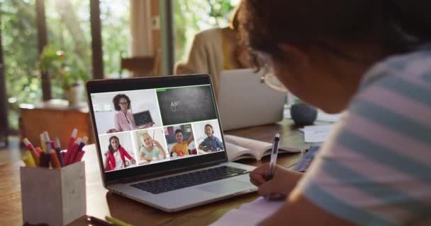 家庭でのオンラインレッスンのためにラップトップを使用して女子高生 画面上で多様な教師とクラスと グローバルコミュニケーション技術とオンライン初等教育の概念デジタル複合ビデオ — ストック動画