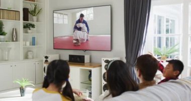 Mutlu bir ailenin evde oturup televizyonda judo maçı izlemesinin birleşimi. spor, rekabet, eğlence ve teknoloji konsepti dijital olarak oluşturulmuş video.