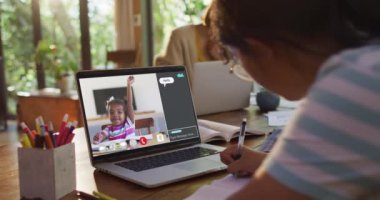 Liseli kız evde online ders için dizüstü bilgisayar kullanıyor. Okul arkadaşı ve internette sohbet ediyor. küresel iletişim teknolojisi ve çevrimiçi ilköğretim konsepti, dijital kompozit video.