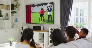 Mutlu bir ailenin evde oturup televizyonda rugby maçı izlemesinin birleşimi. spor, rekabet, eğlence ve teknoloji konsepti dijital olarak oluşturulmuş video.