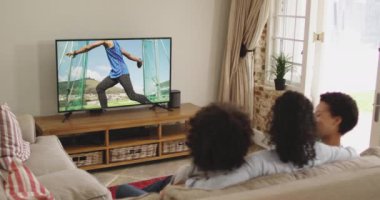 Mutlu bir ailenin evde oturup televizyondaki disk atletizm etkinliğini izlemesinin birleşimi. spor, rekabet, eğlence ve teknoloji konsepti dijital olarak oluşturulmuş video.