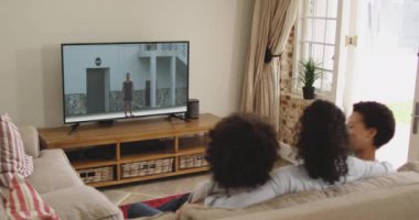 Mutlu bir ailenin evde oturup TV 'de atletizm maçı izlemesinin birleşimi. spor, rekabet, eğlence ve teknoloji konsepti dijital olarak oluşturulmuş video.