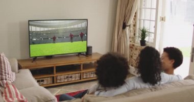 Mutlu bir ailenin evde oturup televizyonda rugby maçı izlemesinin birleşimi. spor, rekabet, eğlence ve teknoloji konsepti dijital olarak oluşturulmuş video.