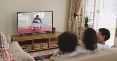 Mutlu bir ailenin evde oturup televizyonda judo maçı izlemesinin birleşimi. spor, rekabet, eğlence ve teknoloji konsepti dijital olarak oluşturulmuş video.