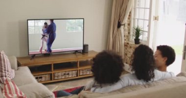 Mutlu bir ailenin evde oturup televizyonda judo maçı izlemesinin birleşimi. spor, rekabet, eğlence ve teknoloji konsepti dijital olarak oluşturulmuş video.