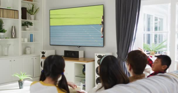 Kompozyt Szczęśliwej Rodziny Siedzącej Razem Domu Oglądającej Lekkoatletykę Biegającą Telewizji — Wideo stockowe