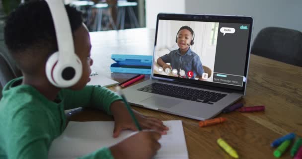 男同学在家里用笔记本电脑上网上课 他的同事和网上聊天在屏幕上 全球通信技术与在线初等教育概念 数字复合视频 — 图库视频影像
