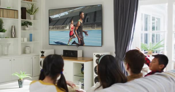 幸せな家族が一緒にテレビで実行している陸上競技を見て家に座っての複合 スポーツ エンターテイメント テクノロジーの概念をデジタルで生成したビデオ — ストック動画
