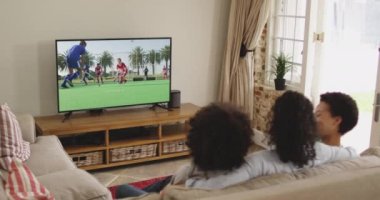 Mutlu bir ailenin evde oturup TV 'de hokey maçı izlemesinin birleşimi. spor, rekabet, eğlence ve teknoloji konsepti dijital olarak oluşturulmuş video.