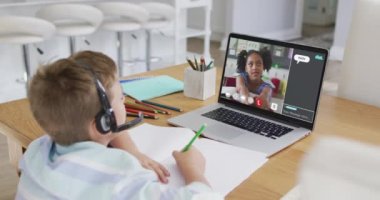 Okullu çocuk evde online ders için dizüstü bilgisayar kullanıyor. Okul arkadaşı ve internette sohbet ediyor. küresel iletişim teknolojisi ve çevrimiçi ilköğretim konsepti, dijital kompozit video.