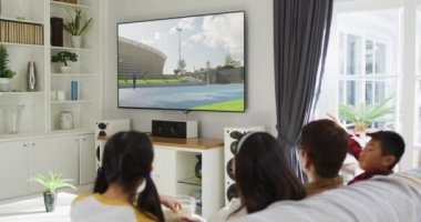 Mutlu bir ailenin evde oturup TV 'de atletizm cirit yarışmasını izlemesinin birleşimi. spor, rekabet, eğlence ve teknoloji konsepti dijital olarak oluşturulmuş video.