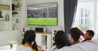 Mutlu bir ailenin evde oturup televizyonda rugby maçı izlemesinin birleşimi. spor, rekabet, eğlence ve teknoloji konsepti dijital olarak oluşturulmuş video.