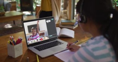 Kızın evde online ders için dizüstü bilgisayar kullandığı ve kızın ekranda elini kaldırdığı birleşik video. küresel iletişim teknolojisi ve çevrimiçi ilköğretim konsepti, dijital olarak oluşturulmuş video.