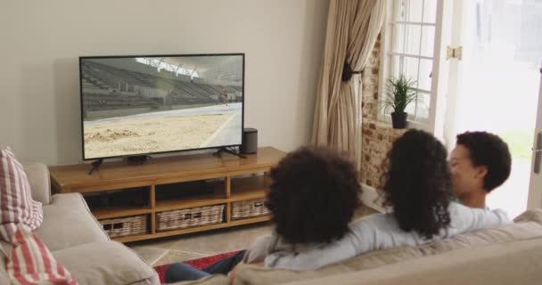 Compuesto Familia Feliz Sentados Casa Juntos Viendo Atletismo Salto Largo — Vídeos de Stock