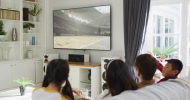 Mutlu bir ailenin evde oturup uzun atlama müsabakalarını izlemesinin birleşimi. spor, rekabet, eğlence ve teknoloji konsepti dijital olarak oluşturulmuş video.