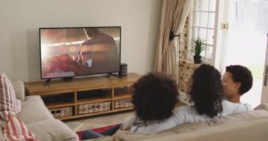Mutlu bir ailenin evde oturup TV 'de spor müsabakalarını izlemesinin birleşimi. spor, rekabet, eğlence ve teknoloji konsepti dijital olarak oluşturulmuş video.